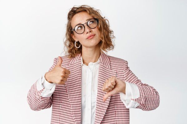 woman-glasses-suit-showing-thumbs-up-down-thinking-about-something-making-decision-weighing-pros-cons-white